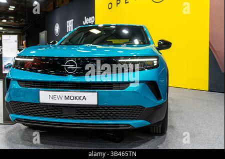 Riga, Lettonia - 25 aprile 2025: Un'impressionante Opel Mokka blu viene esposta in una mostra automobilistica con uno sfondo dinamico. Foto Stock