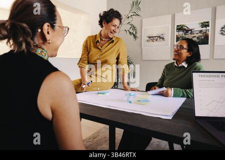 Leader donna sicura di sé che partecipa a una riunione di pianificazione produttiva, condivide idee e collabora con i colleghi sulle strategie di progetto in un'ispirazione Foto Stock