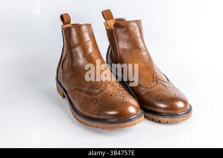 Primo piano di stivali Chelsea in pelle marrone con design a punta alata in brogue e suola robusta. Foto Stock