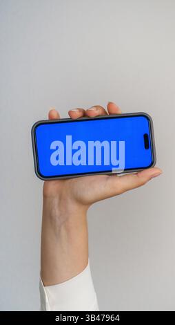 modello con schermata blu vuota del telefono cellulare. mani di adolescente che tiene in mano messaggi di testo usando il cellulare.sfondo spazio vuoto per la pubblicità. contatto con i lavoratori Foto Stock