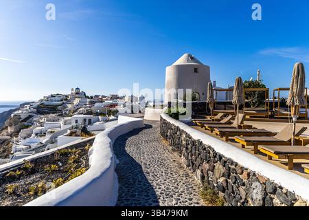 Santorini, Grecia - 15 ottobre 2024: Sentiero panoramico in ciottoli a Santorini che conduce a case bianche e viste mozzafiato. Foto Stock