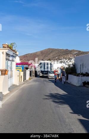 Santorini, Grecia - 15 ottobre 2024: Trafficata strada principale di Oia con un autobus turistico di passaggio e pedoni che passeggiano accanto ai tradizionali edifici imbiancati Foto Stock