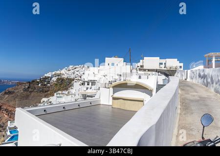 Santorini, Grecia - 15 ottobre 2024: Strada panoramica di Santorini con case bianche e cielo blu. Splendida architettura greca su una scogliera Foto Stock