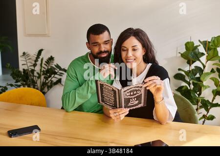 Una coppia sorridente si siede da vicino in un bar, condividendo momenti mentre leggono il menu insieme. Foto Stock