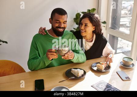 Una coppia felice si diverte con un caffè e un dessert in un'affascinante caffetteria, condividendo sorrisi e risate. Foto Stock