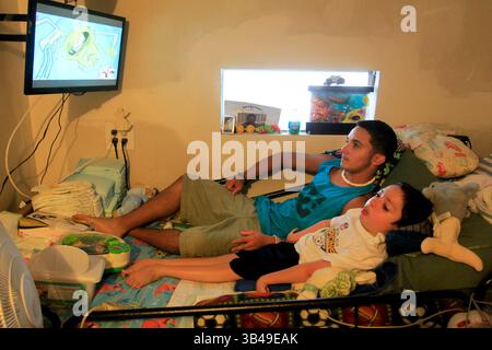 29 giugno 2015 - St. Petersburg, Florida, Stati Uniti - DIRK SHADD | Times.Black Students Achievement gap project:.Ivan Rivera-Otero si arrampica a letto con il fratellino Derrick per guardare la televisione con lui e leggergli nella loro casa mobile nel parco mobile Sun Village di largo. (Foto scattata il 06/29/15).STORIA SOMMARIO: La famiglia di Ivan viveva vicino a tutti l'ospedale pediatrico in modo che il suo fratello malato Derrick potesse ottenere cure mediche regolari. Ma dopo che Ivan era stato vittima di bullismo alla Campbell Park Elementary School, sua madre ha dovuto scegliere tra l'educazione di un figlio e la salute di un figlio. Dopo essermi sentito insicuro Foto Stock