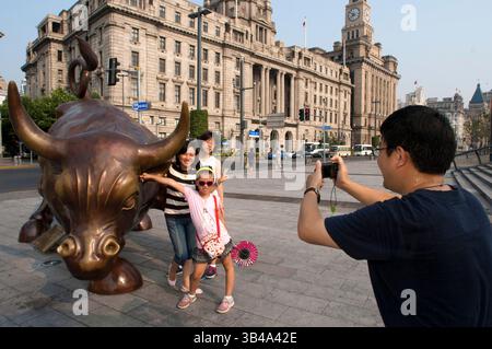 Shanghai Bull sorella di Wall Street Bull. Scultura in bronzo di toro sul Bund a Shanghai Cina. La statua della bolla di carica di Arturo di Modica (chiamata Shanghai Bull, Bund Financial Bull o Bund Bull) sul Bund, Shanghai, Cina. La Shanghai Bull, la Bund Financial Bull o la Bund Bull sono monikers associati ad un derivato della Charging Bull Arturo di Modica installata alla fine di aprile 2010 e svelata sul Bund a Shanghai il 15 maggio 2010. Si dice che l'opera d'arte da 5,000 libbre (2,300 kg) abbia la stessa altezza, lunghezza e peso del New York City Charging Bull Il toro è rossastro come tr Foto Stock
