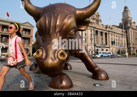 Shanghai Bull sorella di Wall Street Bull. Scultura in bronzo di toro sul Bund a Shanghai Cina. La statua della bolla di carica di Arturo di Modica (chiamata Shanghai Bull, Bund Financial Bull o Bund Bull) sul Bund, Shanghai, Cina. La Shanghai Bull, la Bund Financial Bull o la Bund Bull sono monikers associati ad un derivato della Charging Bull Arturo di Modica installata alla fine di aprile 2010 e svelata sul Bund a Shanghai il 15 maggio 2010. Si dice che l'opera d'arte da 5,000 libbre (2,300 kg) abbia la stessa altezza, lunghezza e peso del New York City Charging Bull Il toro è rossastro come tr Foto Stock