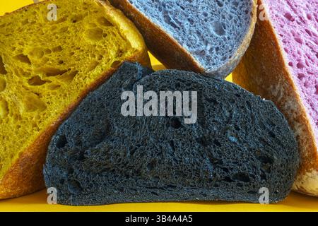 Pane fresco fatto in casa a pasta madre colorata. Fette di pane isolate su sfondo giallo, elemento di design. Foto Stock
