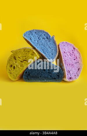 Pane fresco fatto in casa a pasta madre colorata. Fette di pane isolate su sfondo giallo, elemento di design. Foto Stock