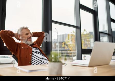 Gli auricolari professionali sorridono davanti a un'elegante scrivania con grandi finestre. Foto Stock