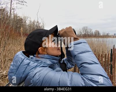 Un momento dettagliato di una donna amante della natura che scansiona l'orizzonte, circondato da rami secchi e cieli ricoperti. Foto Stock