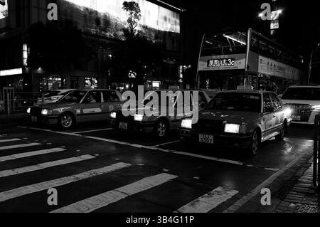 Hong Kong - 2 febbraio 2025 - iconici taxi di Hong Kong si trovano in formazione sotto il bagliore della città Foto Stock