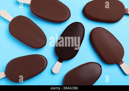 Individualità, unicità, diversa. Gelato ricoperto di glassa di cioccolato fondente, tra gli altri, ricoperto di cioccolato al latte su sfondo azzurro, piatto Foto Stock