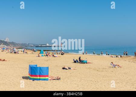 Middle Chine Beach, Bournemouth, Regno Unito - 30 aprile 2025: Bagni di sole con Bournemouth Pier sullo sfondo. Foto Stock