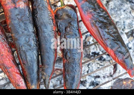 Peperoni rossi arrostiti grigliati sul fuoco aperto con pelli blister e finitura Smoky Foto Stock