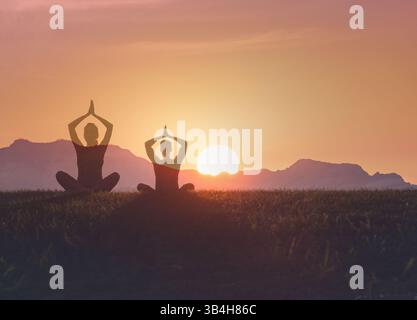 Coppia che fa yoga al tramonto. Meditazione pacifica nella natura al tramonto. Foto Stock