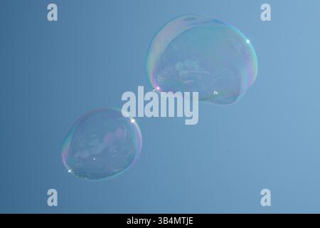 Bolle di sapone giganti che fluttuano contro un cielo blu chiaro. Foto Stock