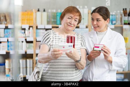 L'acquirente donna scansiona il codice qr del paracetamolo con la farmacista donna Foto Stock