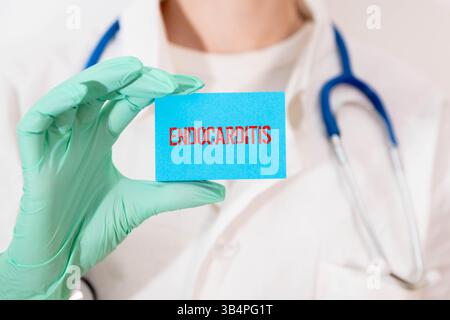 Il medico tiene una scheda con il nome della diagnosi - endocardite. Messa a fuoco selettiva. Concetto medico. Foto Stock