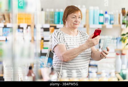 La donna anziana in farmacia scansiona il codice QR sulla crema Foto Stock