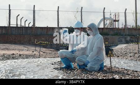 Ecologo di campionamento acqua sostanze chimiche tossiche dal fiume con provetta in vetro e fumo bianco Foto Stock