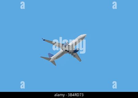 Vista dal basso dell'aereo passeggeri che decolla nel cielo blu Foto Stock