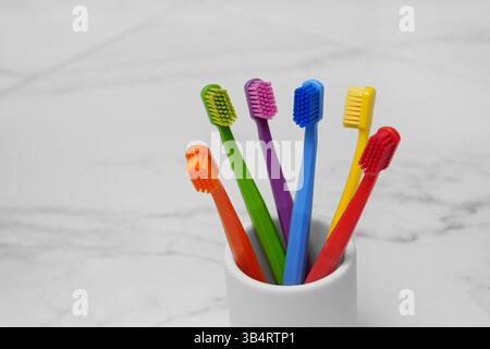 Sei spazzolini colorati in un bicchiere nel bagno. Foto leggera. Posiziona per testo. Foto Stock