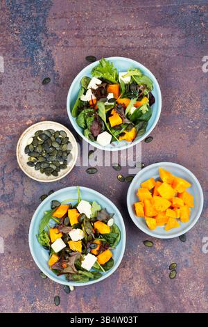 Insalata di verdure fresche con zucca di Hokkaido autunnale, formaggio feta e verdure verdi. Vegano sano. Foto Stock