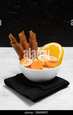 Dolcezza su un piatto con banana arancio e carote. Spuntino vegetariano. Prima colazione. Foto Stock