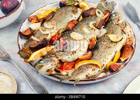 Pesce intero al forno, servito con fichi arrostiti e limone. Foto Stock