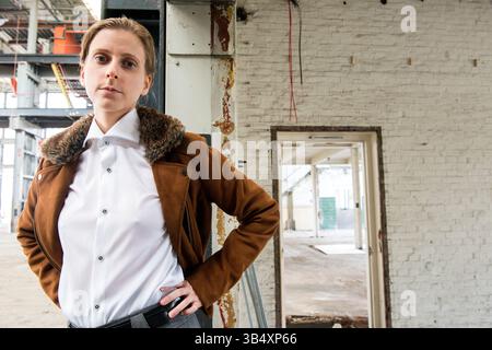 Ritratti donna di genere, che indossa la moda maschile all'interno di un ambiente industriale. Tilburg, Paesi Bassi. MR=SÌ Foto Stock