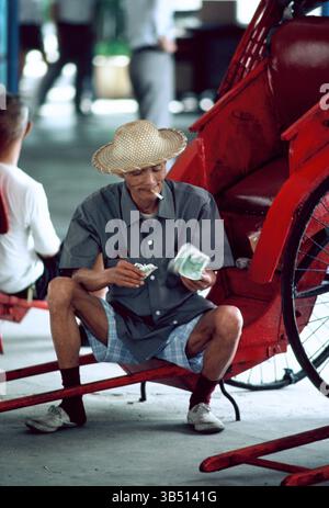 Cina. Hong Kong. Gente del posto, Rickshaw, che conta i soldi. Foto Stock