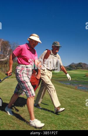 Golfisti senior donna e uomo che camminano sul campo da golf. Foto Stock