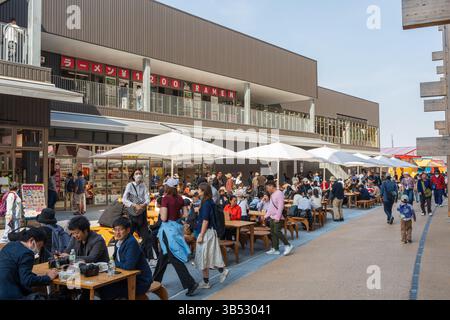 Osaka, Giappone - aprile 30 2025: Persone che riposano e mangiano nell'area designata accanto all'iconico Grand Ring all'Expo 2025 Osaka Kansai. Foto Stock