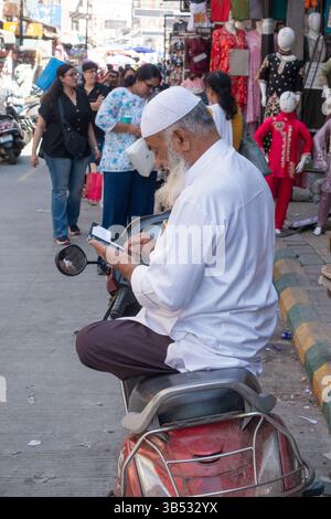 Uomo musulmano seduto a gambe incrociate in moto a Bangalore, Karnataka, India, Asia Foto Stock
