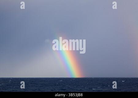 Parte di un arcobaleno colorato e luminoso in mare aperto. Foto Stock