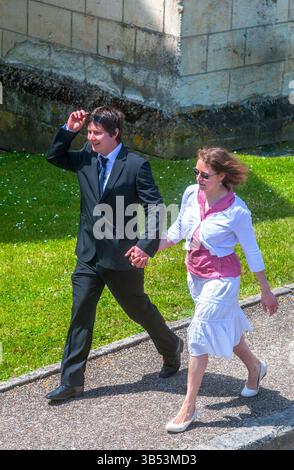 Coppia felice che cammina insieme tenendosi per mano (dopo aver frequentato la chiesa) - Preuilly-sur-Claise, Indre-et-Loire (37), Francia. Foto Stock
