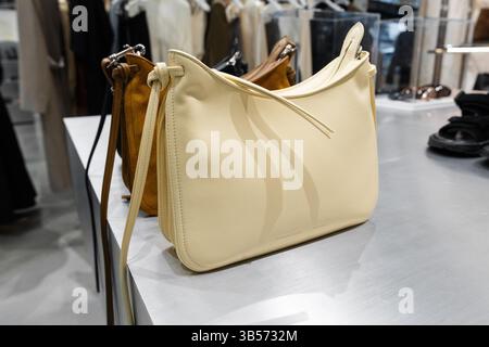 Milano, Italia - 8 aprile 2025: Borsa a spalla Phoebe Philo in pelle crema su banco in metallo. Accessori di moda firmati esposti all'interno della boutique di Milano Foto Stock
