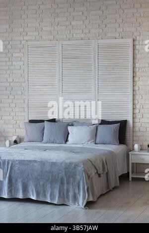 I delicati interni della camera da letto sono in colori chiari, c'è un letto con cuscini e una copertura. Ottimo posto per dormire Foto Stock