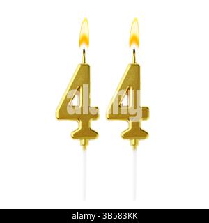 Bruciare candele dorate che compongono il numero 44 su sfondo bianco. Decorazioni festive per il compleanno o altre date speciali Foto Stock