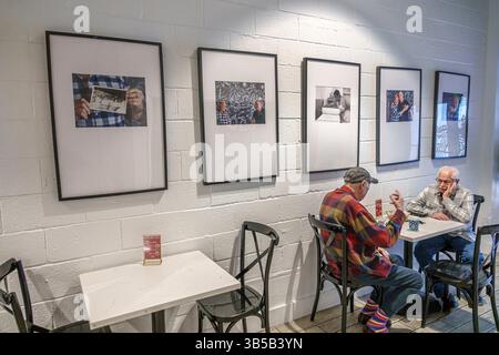 Miami Beach, Florida, Alton Road, ristorante CAO, interno, caffetteria interna, tavoli e sedie, pareti in mattoni dipinti di bianco, mostre fotografiche con cornice nera Foto Stock