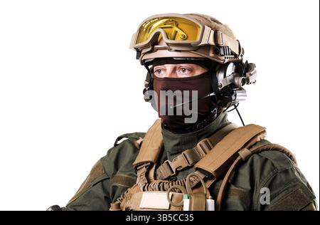 Ritratto di un soldato dotato di equipaggiamento tattico, tra cui casco, cuffie e occhiali protettivi, che presenta un comportamento professionale, un ag isolato Foto Stock