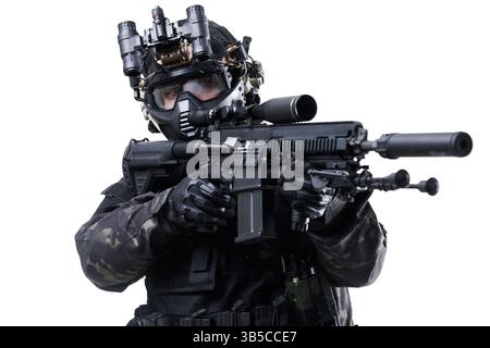 Operativo tattico in mimetismo militare con armamenti avanzati, equipaggiato con equipaggiamento da combattimento e occhiali per la visione notturna, che enfatizzano la prontezza e il pre-attacco Foto Stock