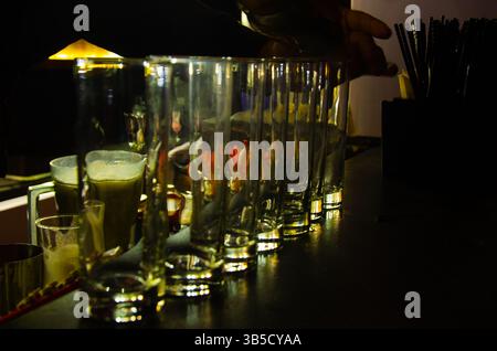 Una tazza di vetro piena di cubetti di ghiaccio collocati su un tavolo in un pub è un'immagine comune che rappresenta una bevanda fredda o un momento rinfrescante. Foto Stock