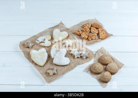 diversi tipi di biscotti su un sacco su uno sfondo di legno bianco. posizione piatta. Foto Stock