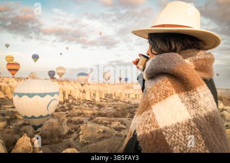 Donna turistica che guarda le mongolfiere nel punto panoramico della valle dell'amore in Cappadocia, Turchia. Concetto di viaggio felice in Turchia. Donna su un enjo in cima a una montagna Foto Stock