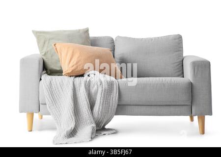 Divano con cuscini e coperta su sfondo bianco Foto Stock