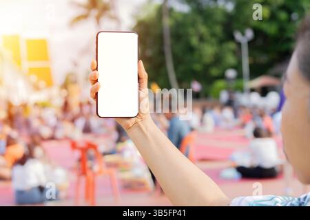 Immagine ravvicinata di mani maschili che tengono lo smartphone con schermo isolato nella strada dello shopping della città. Copia spazio, messa a fuoco selettiva. Foto Stock