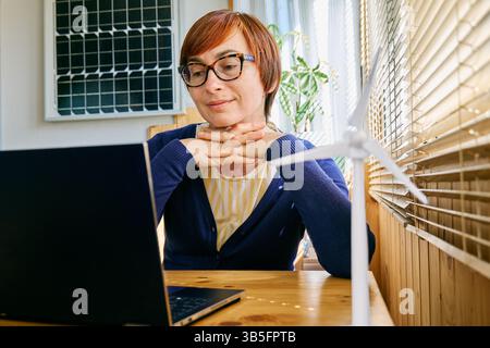 Donna d'affari che lavora in un ufficio domestico nel settore delle energie rinnovabili. Foto Stock